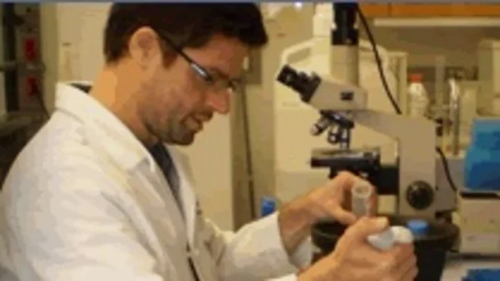 Julian Antonio Martinez looking through a microscope